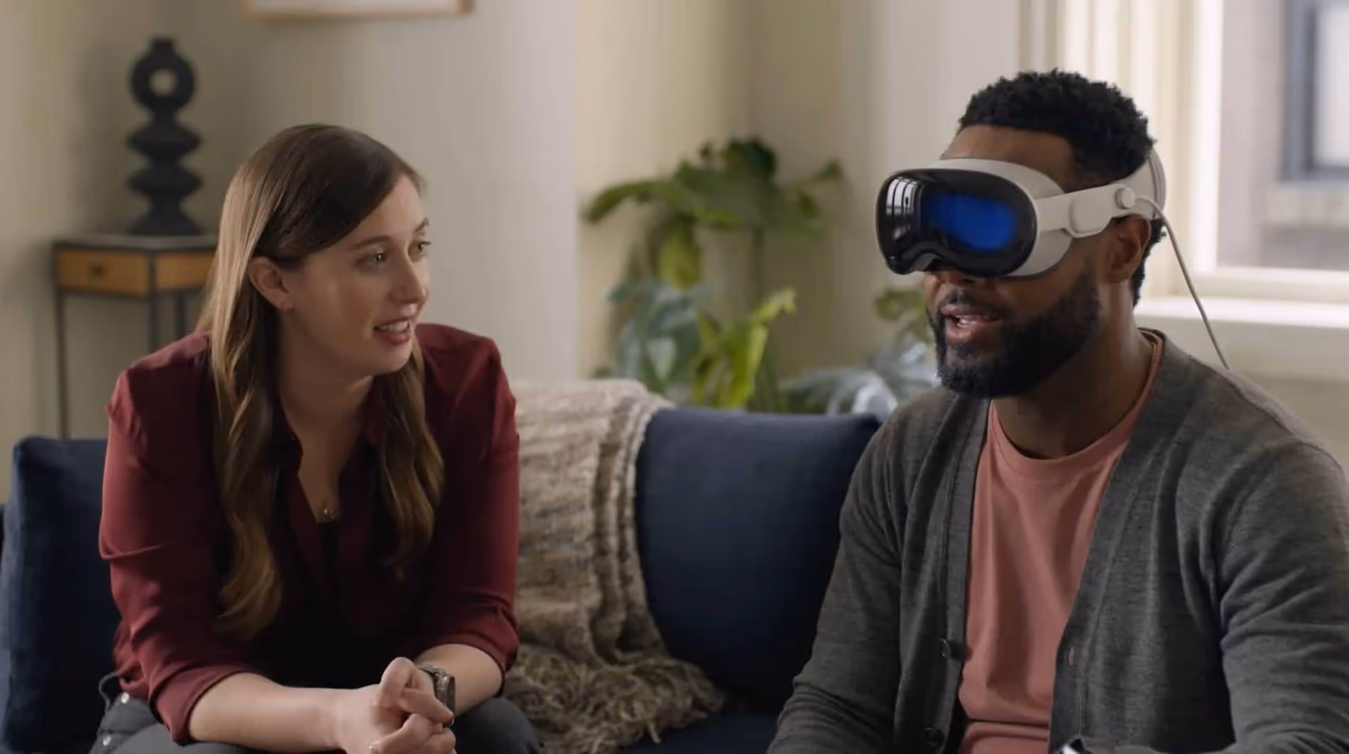 Osoba w goglach Apple Vision Pro siedząca na kanapie obok rozmówczyni.