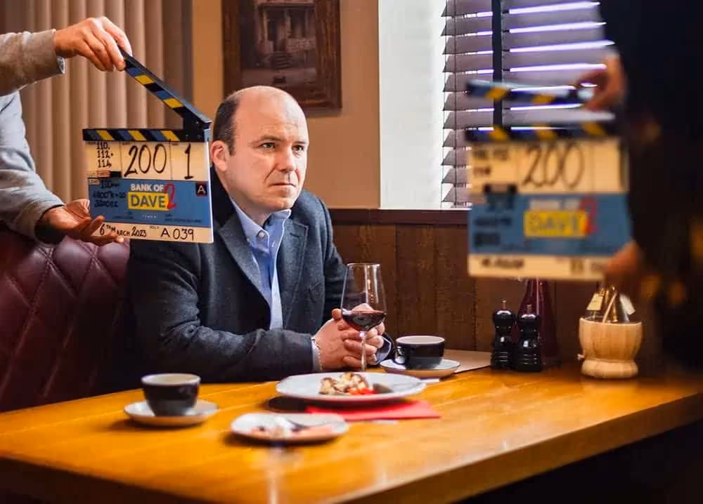Plan produkcji Netflix: aktor przy stole i klaps filmowy na pierwszym planie.